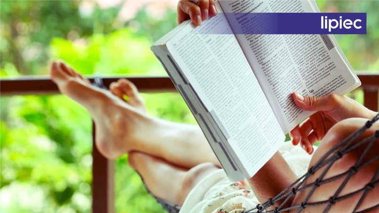 Książki miesiąca: Lipiec Książka w zielonej okładce leżąca na piasku, na niej okulary przeciwsłoneczne