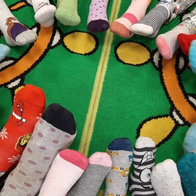 Przedszkolaki prezentują swoje kolorowe skarpetki z okazji Dnia Osób z Zespołem Downa