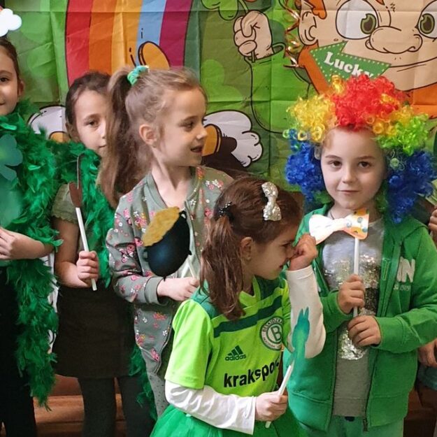 Dzieci w ubraniach w zielonym kolorze, demonstrują różne elementy związane z obchodzonym świętem