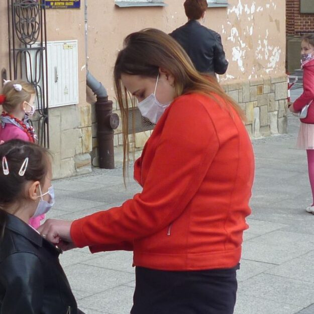 Matka przypina dziecku kokardkę