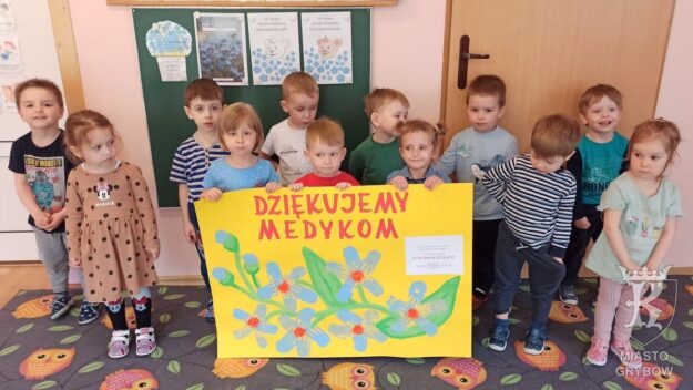 Grupa stojących dzieci trzyma plakat „Dziękujemy Medykom”