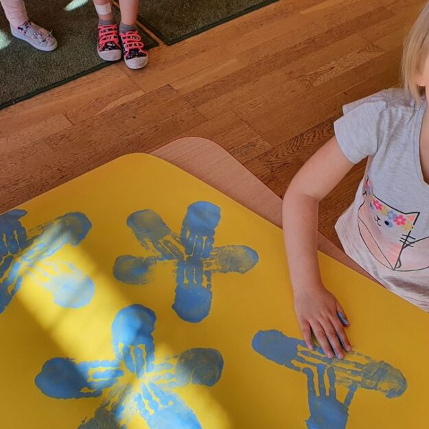 Dziewczynka odbija rękę wykonując kwiaty na plakacie