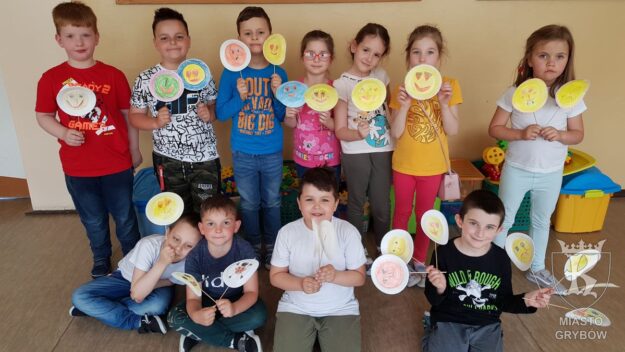 Grupa dzieci prezentująca swoje emotikony na patykach