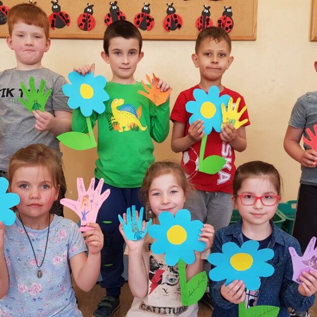 Dzieci pozują do zdjęcia z wykonanymi przez siebie pracami