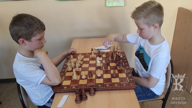 Dwójka chłopców siedzi przy stoliku podczas rozgrywek szachowych