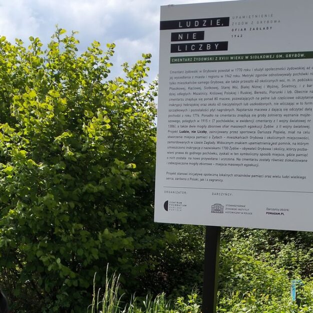 Uczennica odczytująca informacje dotyczące historii cmentarza żydowskiego oraz projektu "Ludzie, nie liczby"