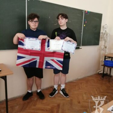 Uczniowie klasy 7b - Konrad i Norbert trzymają rozłożoną flagę Wielkiej Brytanii oraz dyplomy