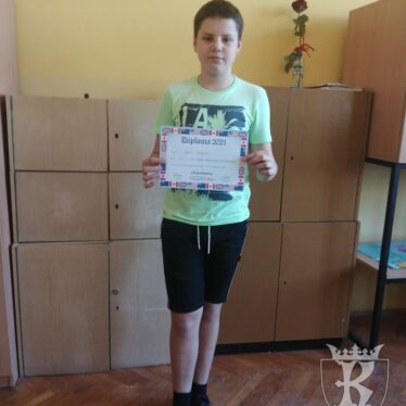 Uczeń klasy 7a - Rafał, trzyma w rękach otrzymany dyplom