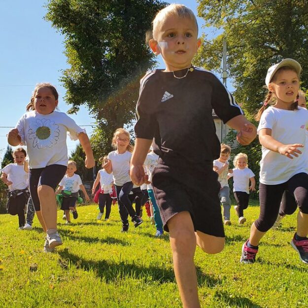 Dzieci biegną po trawie