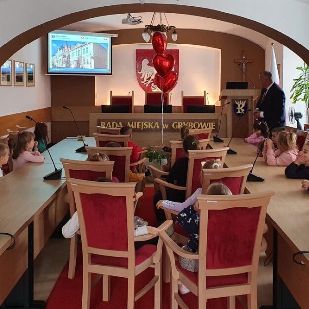 Siedzące dzieci słuchają przemówienia Burmistrza