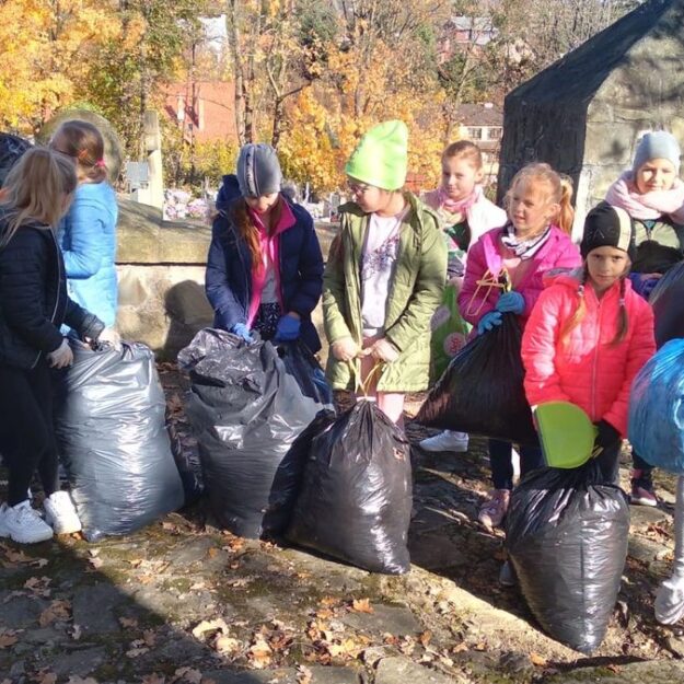 Dzieci stoją i trzymają worki z odpadami
