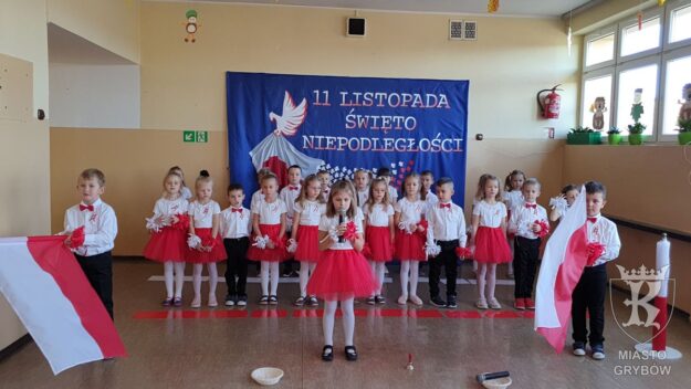 Dziewczynka śpiewa do mikrofonu, dwaj chłopcy machają flagami