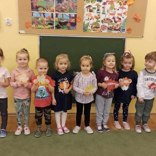 Dzieci stoją w szeregu trzymając w ręce listki z prawami