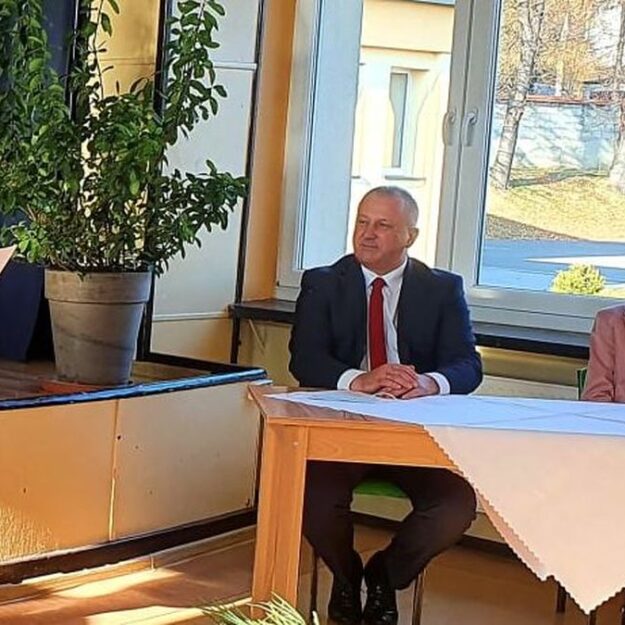 Na fotografii uczestniczka konkursu recytująca swój wiersz, obok przy stoliku zasiada jury