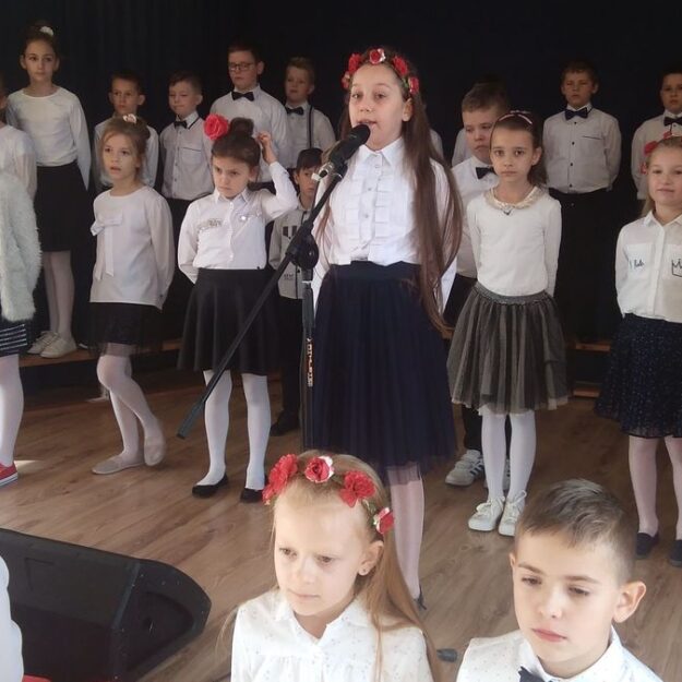 Dzieci na scenie z dziewczynką przy mikrofonie na jej środku
