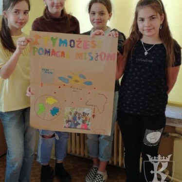 Dzieci z plakatem promującym akcje pod tytułem „I ty możesz pomagać misjom”