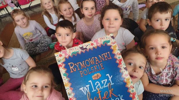 Dzieci siedzą na dywanie a na pierwszym planie książka - rymowanki polskie