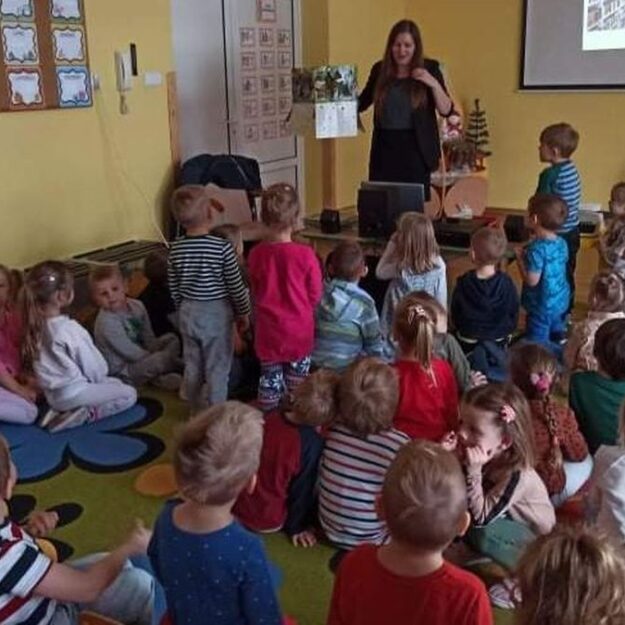 Autorka pokazuje dzieciom książkę z rozkładanymi elementami