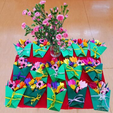 Na stoliku - wazon z goździkami oraz upominki dla rodziców przygotowane przez dzieci