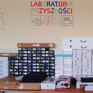 Pudła ze sprzętem elektronicznym, w tle niedokończony malowany napis LABORATORIA PRZYSZŁOŚCI