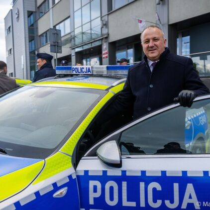 Burmistrz Grybowa stoi za otwartymi drzwiami radiowozu