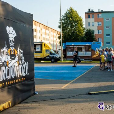 Reklama ŻARCIOWOZY - ZLOT FOODTRACKÓW - w tle stoją samochody sprzedające jedzenie