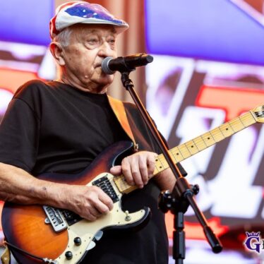 Gitarzysta zespołu 2 plus 1 śpiewa do mikrofonu