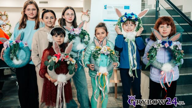 Grupa dzieci z dumą prezentuje zrobione przez siebie wianki