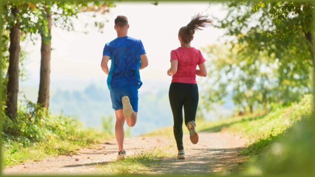 Widok od tyłu biegnącej leśną drogą pary biegaczy