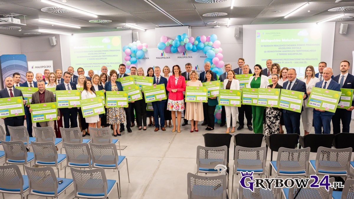 Grupa samorządowców prezentuje tablice z kwotami, które otrzymali w ramach projektu „Małopolska Maluchom w 2026 roku”