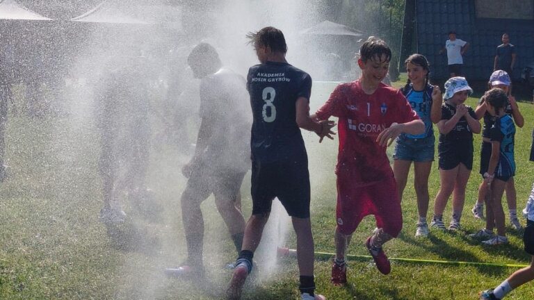Zakończenie sezonu Akademii MOSiR Grybów Grupa dzieci podczas wspólnej zabawy przy wodnej kurtynie